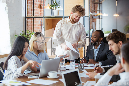 Image of Diverse group of co-workers having casual discussion in office. Executives during friendly discussion, month reporting, creative meeting