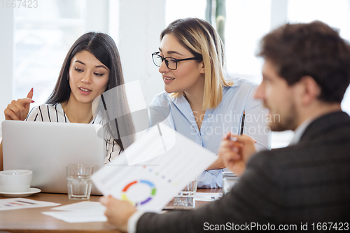 Image of Diverse group of co-workers having casual discussion in office. Executives during friendly discussion, month reporting, creative meeting