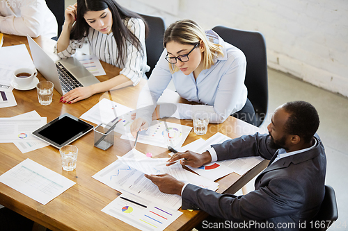 Image of Diverse group of co-workers having casual discussion in office. Executives during friendly discussion, month reporting, creative meeting. Top view.