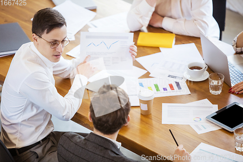 Image of Diverse group of co-workers having casual discussion in office. Executives during friendly discussion, month reporting, creative meeting. Top view.