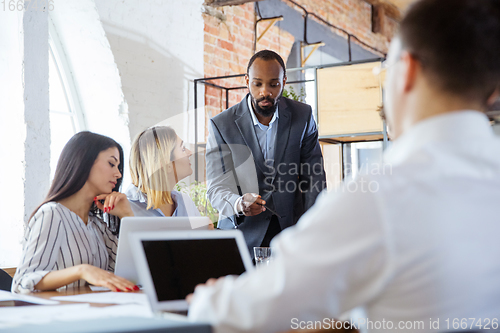 Image of Diverse group of co-workers having casual discussion in office. Executives during friendly discussion, month reporting, creative meeting