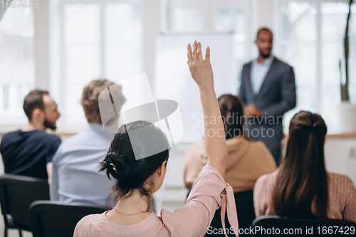 Image of Male speaker giving presentation in hall at workshop. Audience or conference hall. Rear view of unrecognized participants.