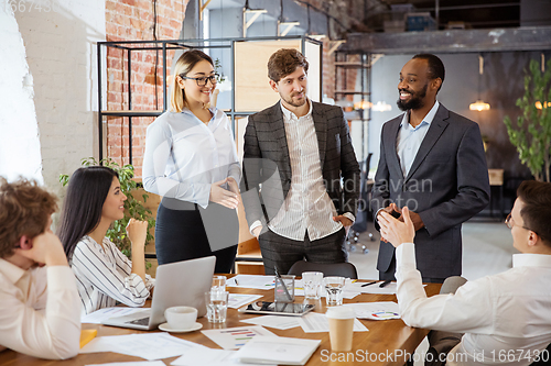 Image of Diverse group of co-workers having casual discussion in office. Executives during friendly discussion, month reporting, creative meeting