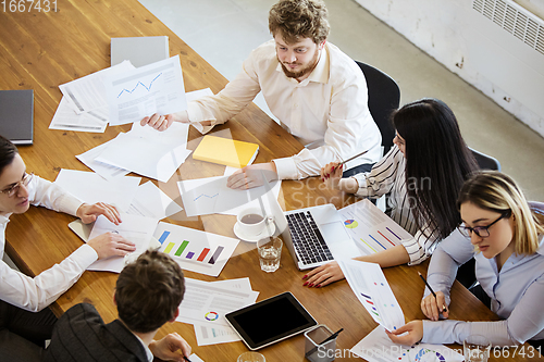 Image of Diverse group of co-workers having casual discussion in office. Executives during friendly discussion, month reporting, creative meeting. Top view.