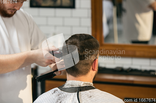 Image of Close up master barber, stylist does the hairstyle to guy, young man. Professional occupation, male beauty concept