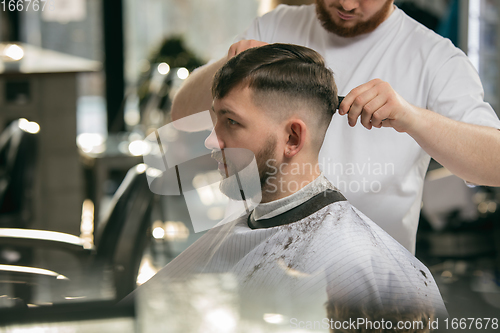 Image of Close up master barber, stylist does the hairstyle to guy, young man. Professional occupation, male beauty concept