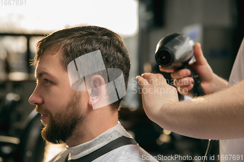 Image of Close up of client of master barber, stylist during getting care of hairstyle. Professional occupation, male beauty concept