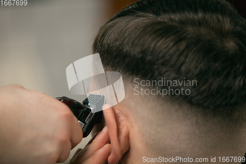 Image of Close up of client of master barber, stylist during getting care of hairstyle. Professional occupation, male beauty concept