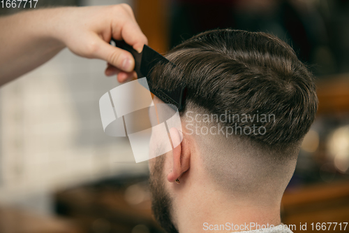 Image of Close up of client of master barber, stylist during getting care of hairstyle. Professional occupation, male beauty concept