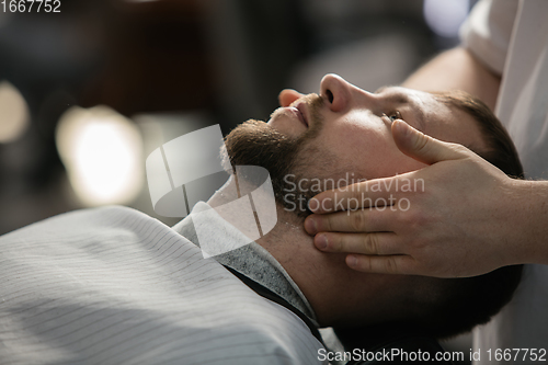 Image of Close up of client of master barber, stylist during getting care of mustache and beard. Professional occupation, male beauty concept