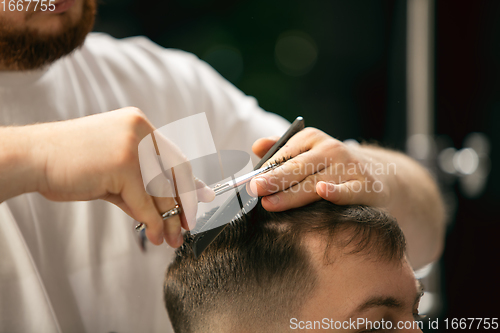 Image of Close up of client of master barber, stylist during getting care of hairstyle. Professional occupation, male beauty concept