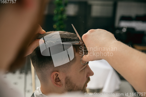 Image of Close up master barber, stylist does the hairstyle to guy, young man. Professional occupation, male beauty concept