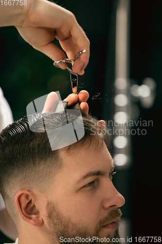 Image of Close up of client of master barber, stylist during getting care of hairstyle. Professional occupation, male beauty concept