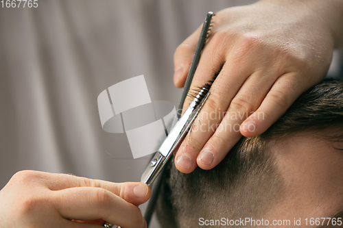 Image of Close up hands of master barber, stylist does the hairstyle to guy, young man. Professional occupation, male beauty concept