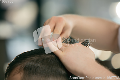 Image of Close up hands of master barber, stylist does the hairstyle to guy, young man. Professional occupation, male beauty concept