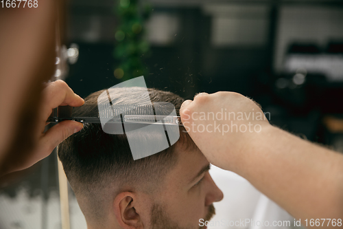 Image of Close up master barber, stylist does the hairstyle to guy, young man. Professional occupation, male beauty concept