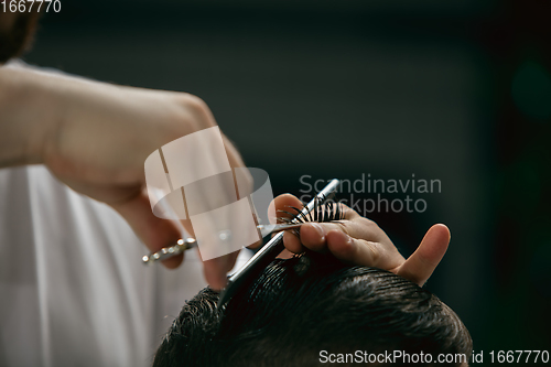 Image of Close up hands of master barber, stylist does the hairstyle to guy, young man. Professional occupation, male beauty concept