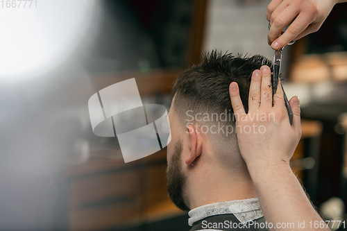 Image of Close up hands of master barber, stylist does the hairstyle to guy, young man. Professional occupation, male beauty concept