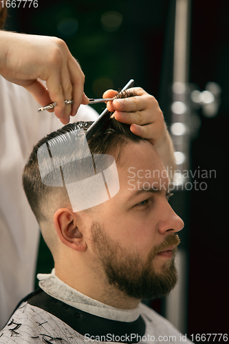 Image of Close up of client of master barber, stylist during getting care of hairstyle. Professional occupation, male beauty concept