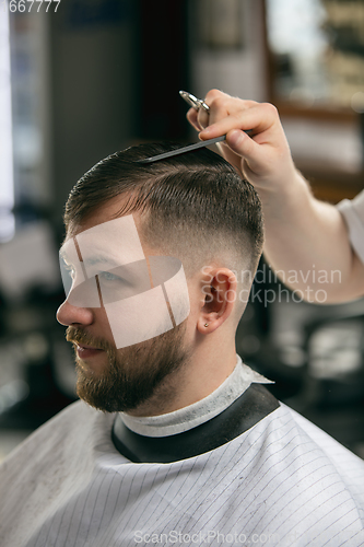 Image of Close up of client of master barber, stylist during getting care of hairstyle. Professional occupation, male beauty concept