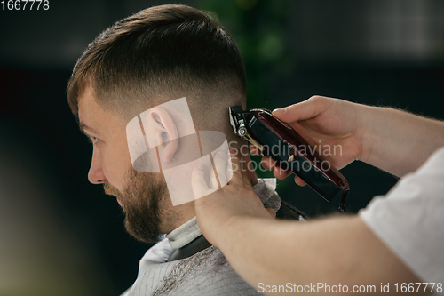 Image of Close up master barber, stylist does the hairstyle to guy, young man. Professional occupation, male beauty concept