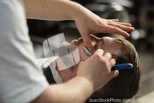 Image of Close up hands of master barber, stylist does the hairstyle to guy, young man. Professional occupation, male beauty concept