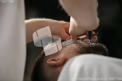 Image of Close up hands of master barber, stylist does the hairstyle to guy, young man. Professional occupation, male beauty concept