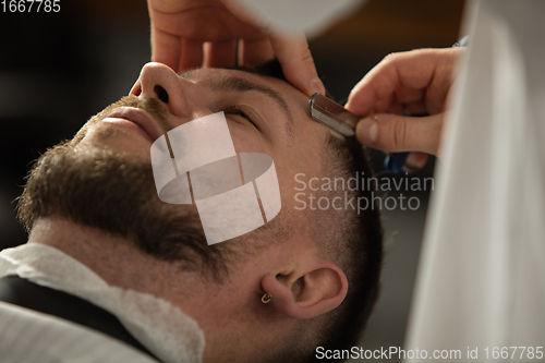 Image of Close up hands of master barber, stylist does the hairstyle to guy, young man. Professional occupation, male beauty concept