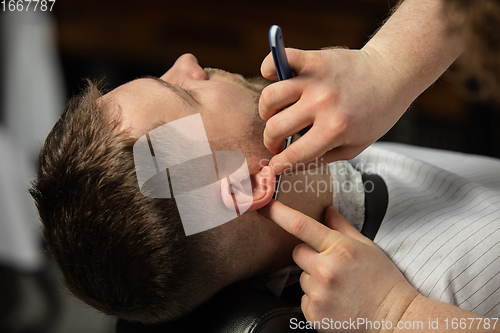 Image of Close up hands of master barber, stylist does the hairstyle to guy, young man. Professional occupation, male beauty concept