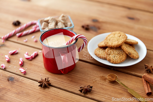 Image of cup of eggnog with candy cane, cookies and anise