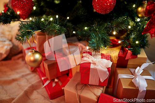 Image of gift boxes under decorated christmas tree at home