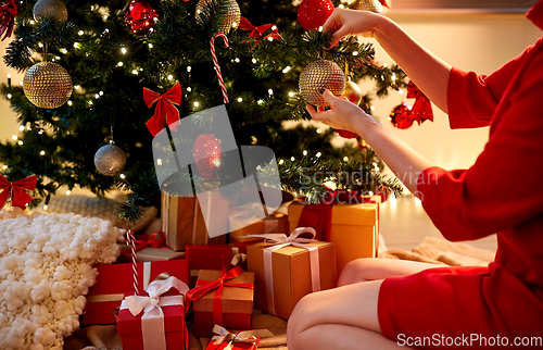 Image of hands decorating christmas tree with ball