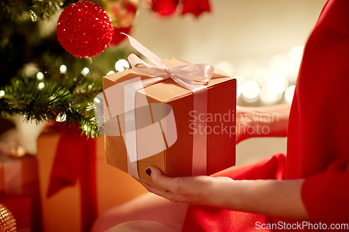 Image of close up of woman with gift box at christmas tree