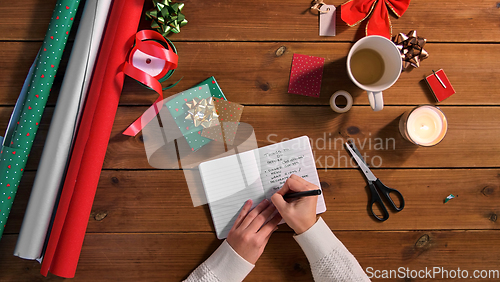 Image of hands writing to do list in notebook on christmas