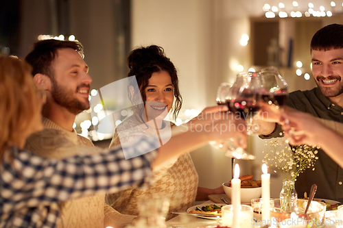 Image of happy friends drinking red wine at christmas party