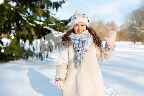 Image of happy little girl waving hand outdoors in winter