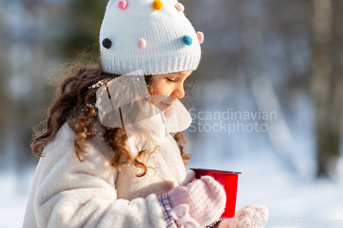 Image of little girl with cup of hot tea in winter park