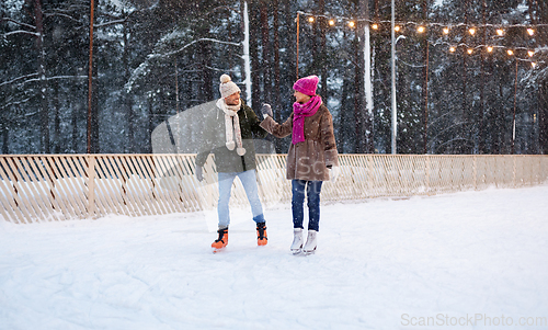 Image of happy couple holding hands on skating rink