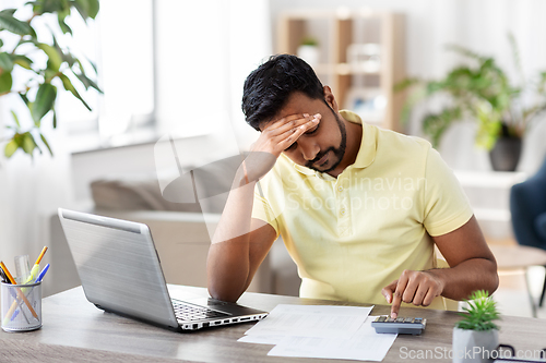 Image of man with calculator and papers working at home