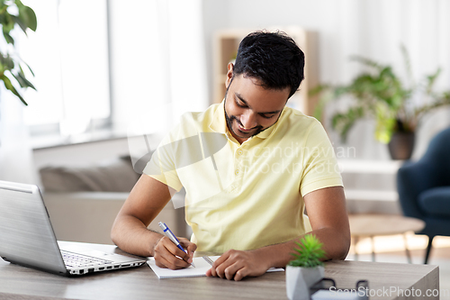 Image of indian man with notebook and laptop at home office