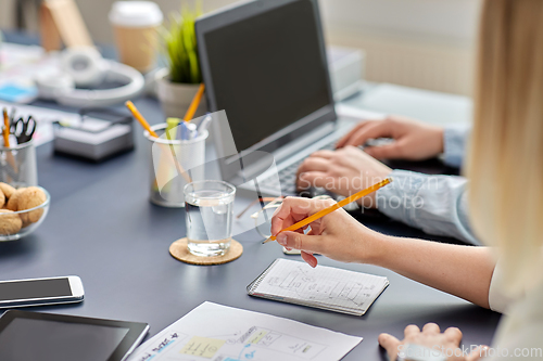 Image of woman with notebook working on ui design at office