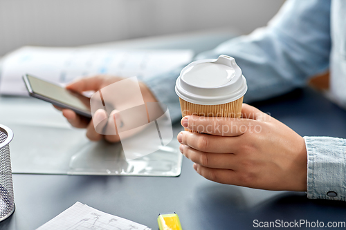 Image of woman with coffee using smartphone at office