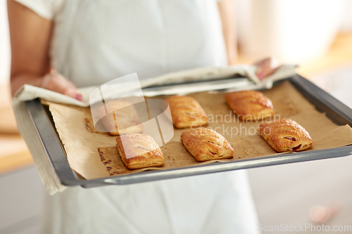 Image of woman holding baking tray with pies at kitchen