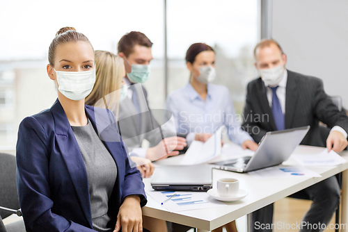 Image of businesswoman in mask with colleagues at office