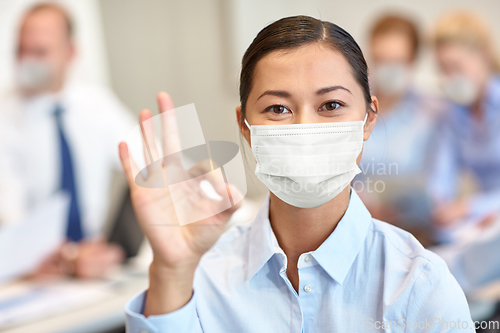 Image of businesswoman in mask showing ok sign at office