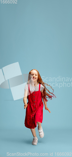 Image of Happy redhair girl isolated on blue studio background. Looks happy, cheerful, sincere. Copyspace. Childhood, education, emotions concept