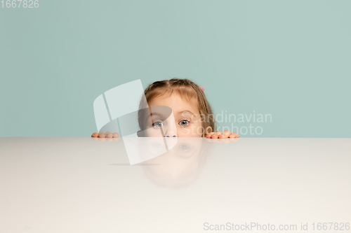 Image of Happy kid, girl isolated on blue studio background. Looks happy, cheerful, sincere. Copyspace. Childhood, education, emotions concept