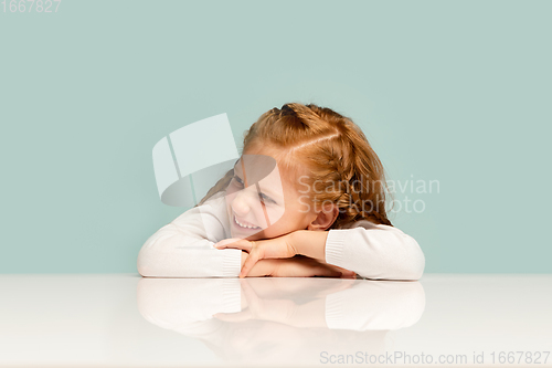 Image of Happy kid, girl isolated on blue studio background. Looks happy, cheerful, sincere. Copyspace. Childhood, education, emotions concept