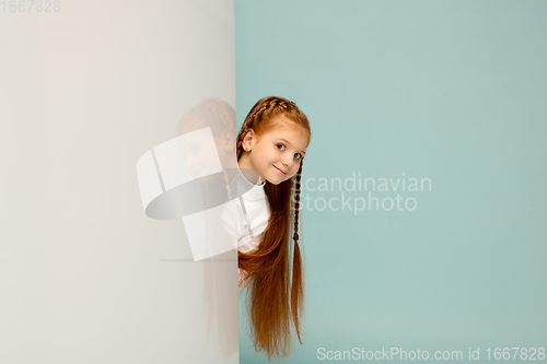 Image of Happy kid, girl isolated on blue studio background. Looks happy, cheerful, sincere. Copyspace. Childhood, education, emotions concept
