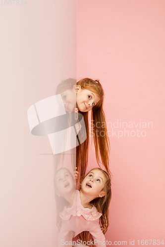 Image of Happy kids, girls isolated on coral pink studio background. Look happy, cheerful, sincere. Copyspace. Childhood, education, emotions concept